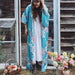 Woman wearing a floral kimono standing outdoors with flowers and a wooden door in the background