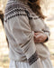 Woman wearing a beige fair isle knit sweater with brown pattern in an outdoor setting