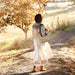 Woman walking along a path in a fair isle knit sweater in a park with autumn foliage