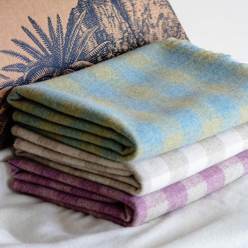 Stack of folded blankets with a branded brown paper bag in the background