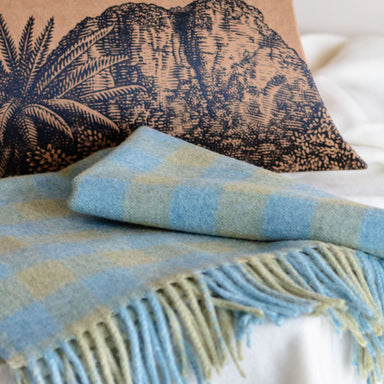 Pillow box packaging with mountain design and 'Grampians Goods Co' text, draped over a blue and green plaid blanket.