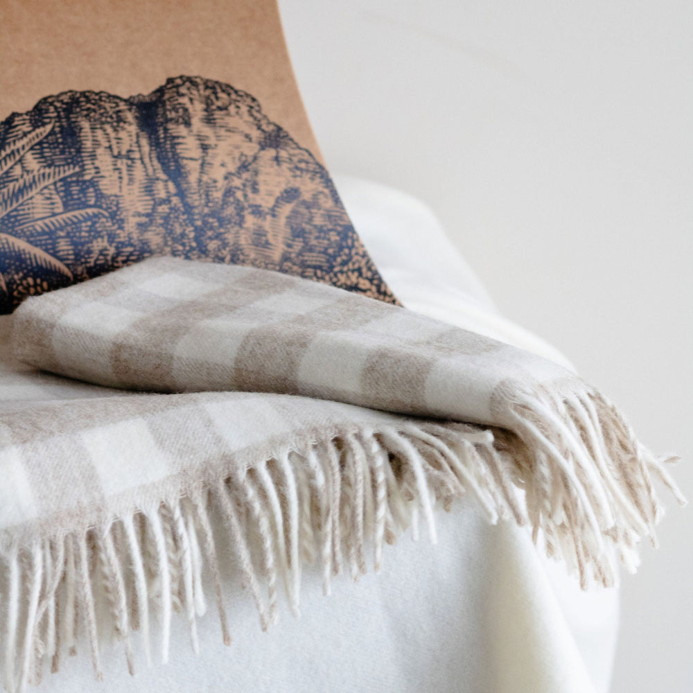 Textured pillow with fringed blanket on a white surface