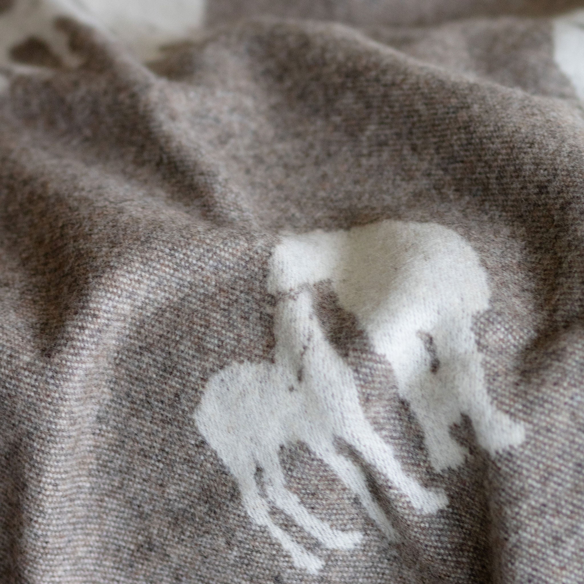 Gray fabric with white animal patterns, possibly sheep, on a textured background.
