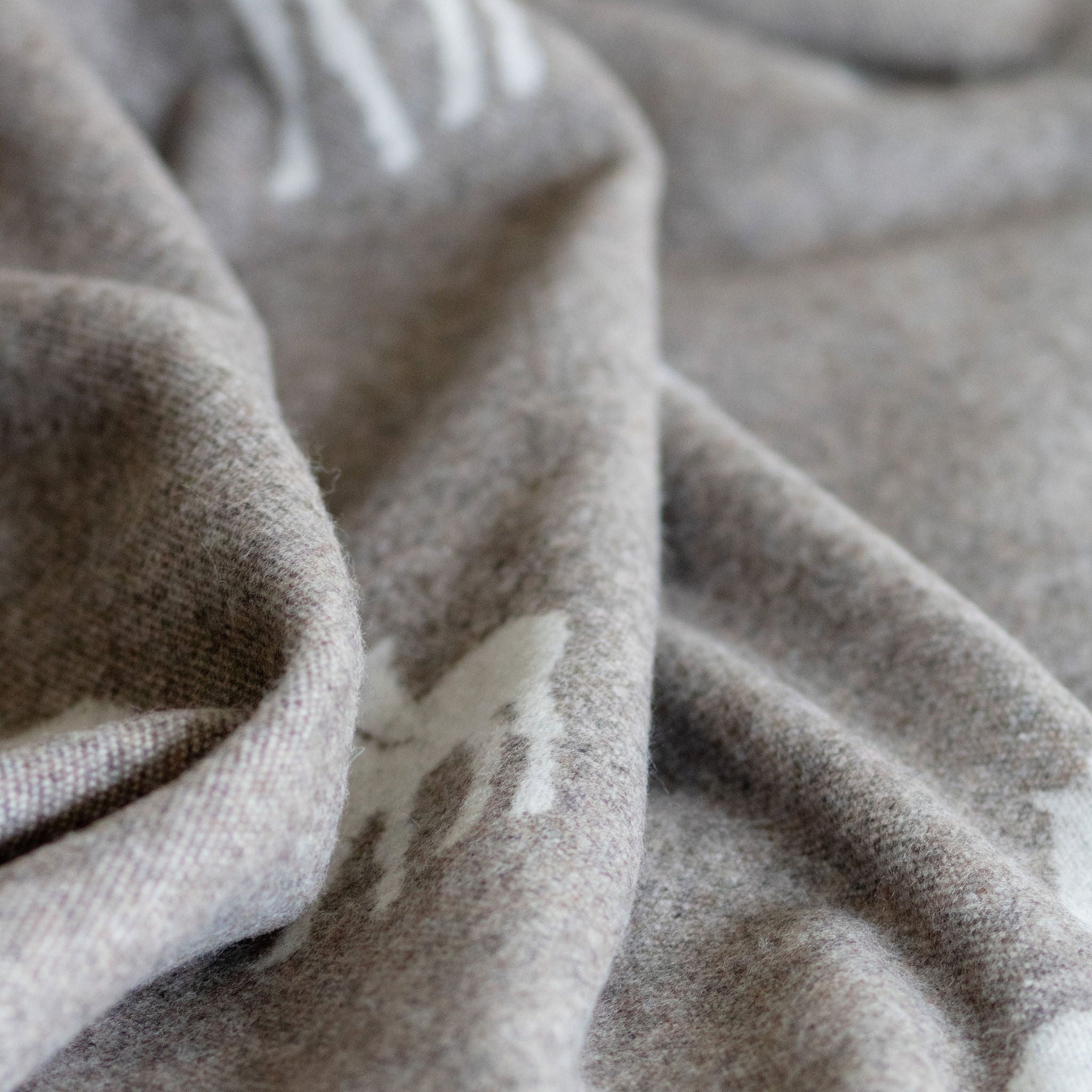 Close-up of textured beige wool blanket with a subtle pattern.