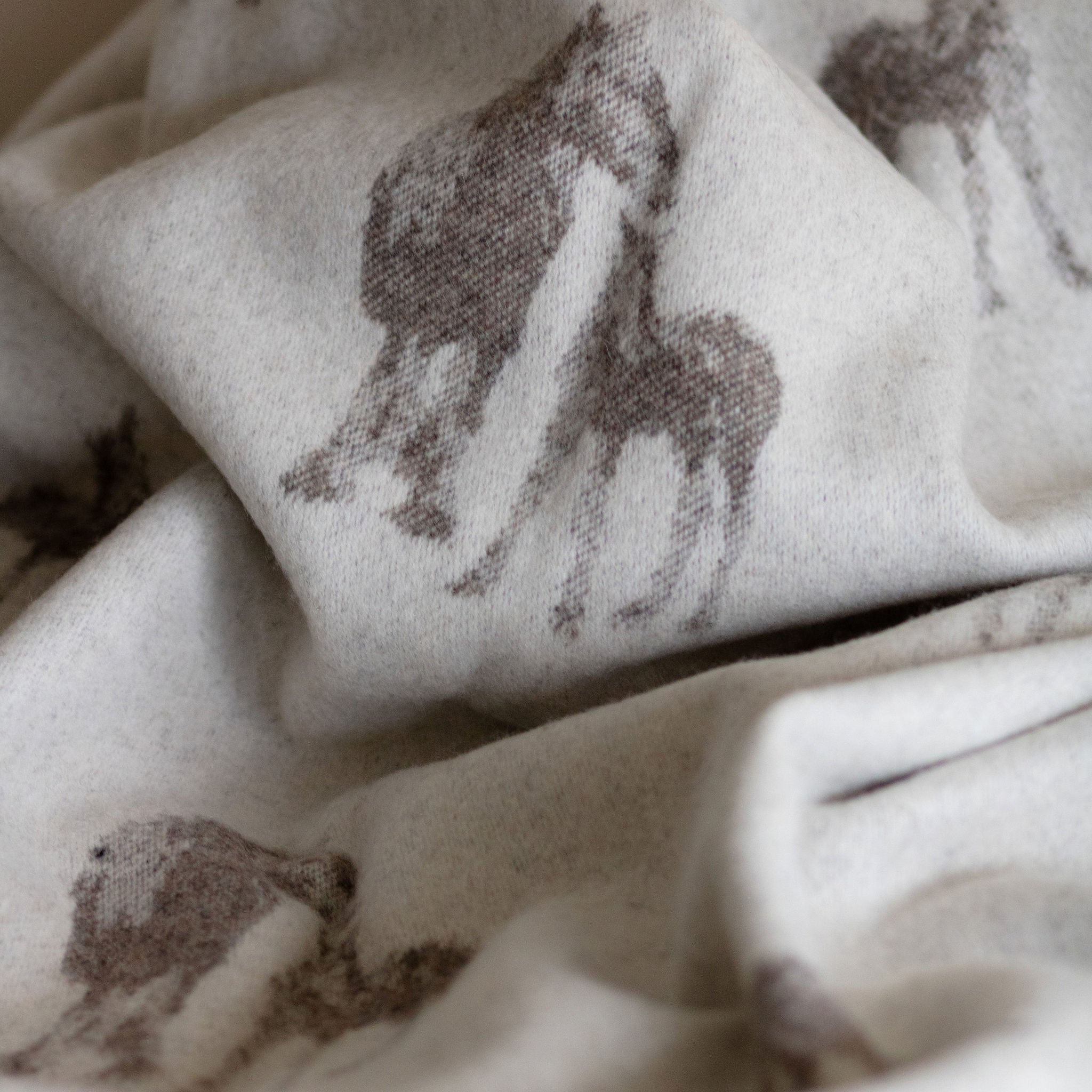 Close-up of wool blanket with subtle horse pattern.