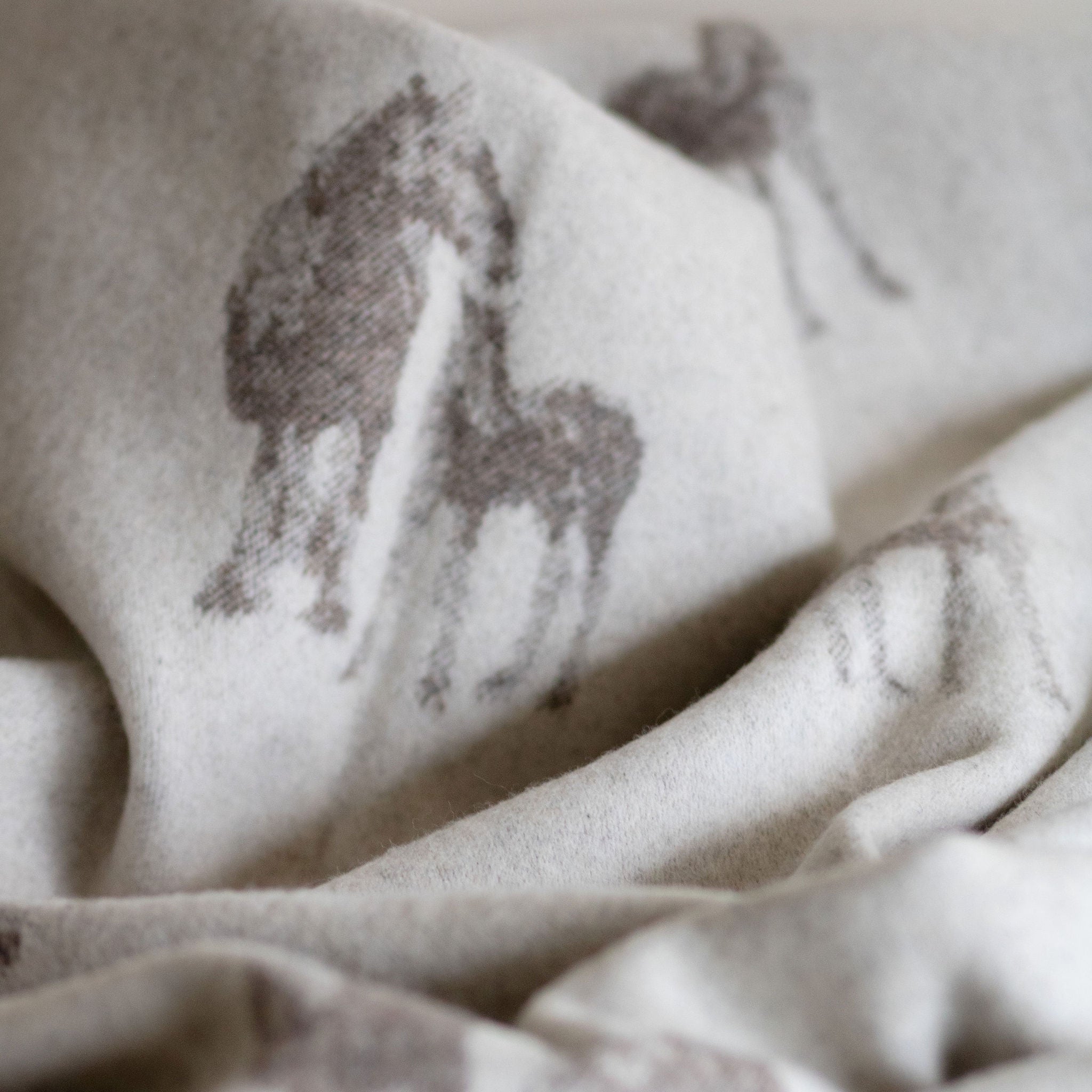 Close-up of wool blanket with subtle horse print on a neutral background.