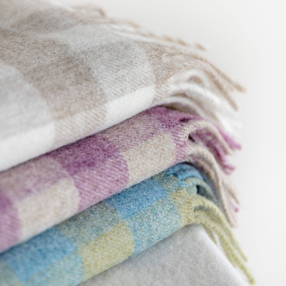Stack of checkered blankets in pastel colors on a light background
