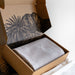 Open cardboard box with a textured interior, containing a gray fabric item on a white surface.