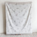 Gray blanket with deer pattern draped over a chair against a white wall.