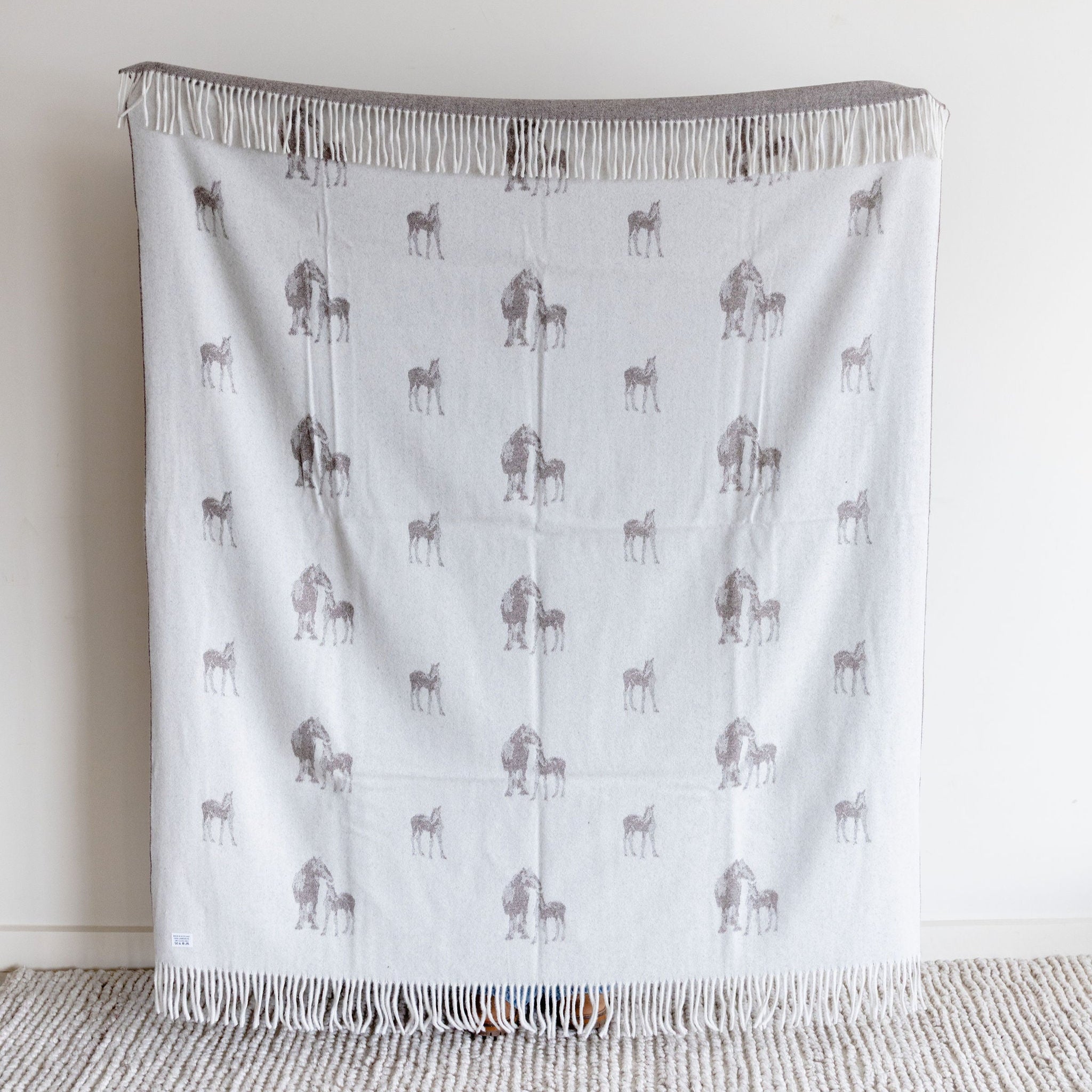 Blanket with horse pattern draped over a chair against a white wall