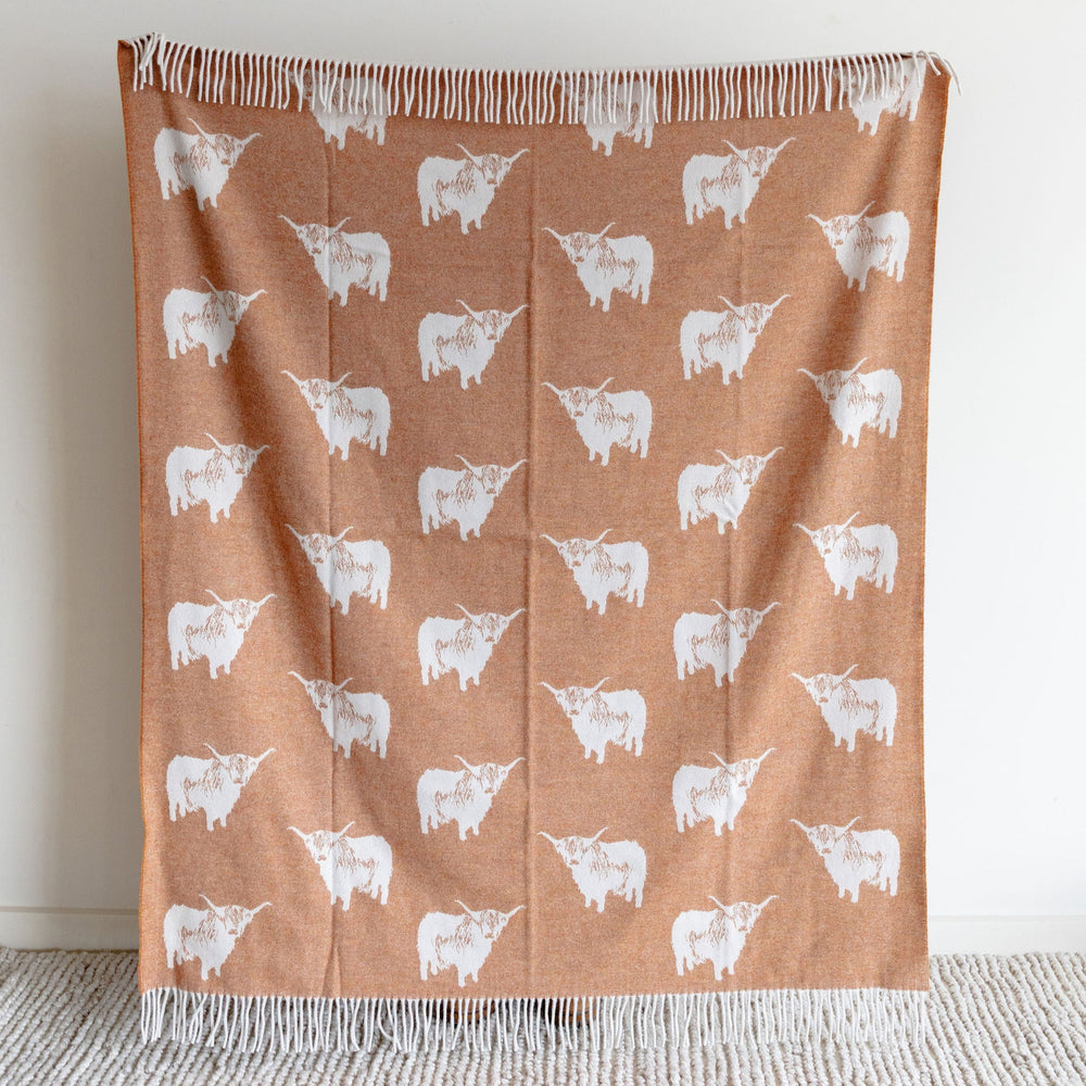 Brown blanket with white cow pattern on a light gray surface