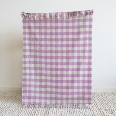 Purple and white checkered blanket on a textured surface with a white background