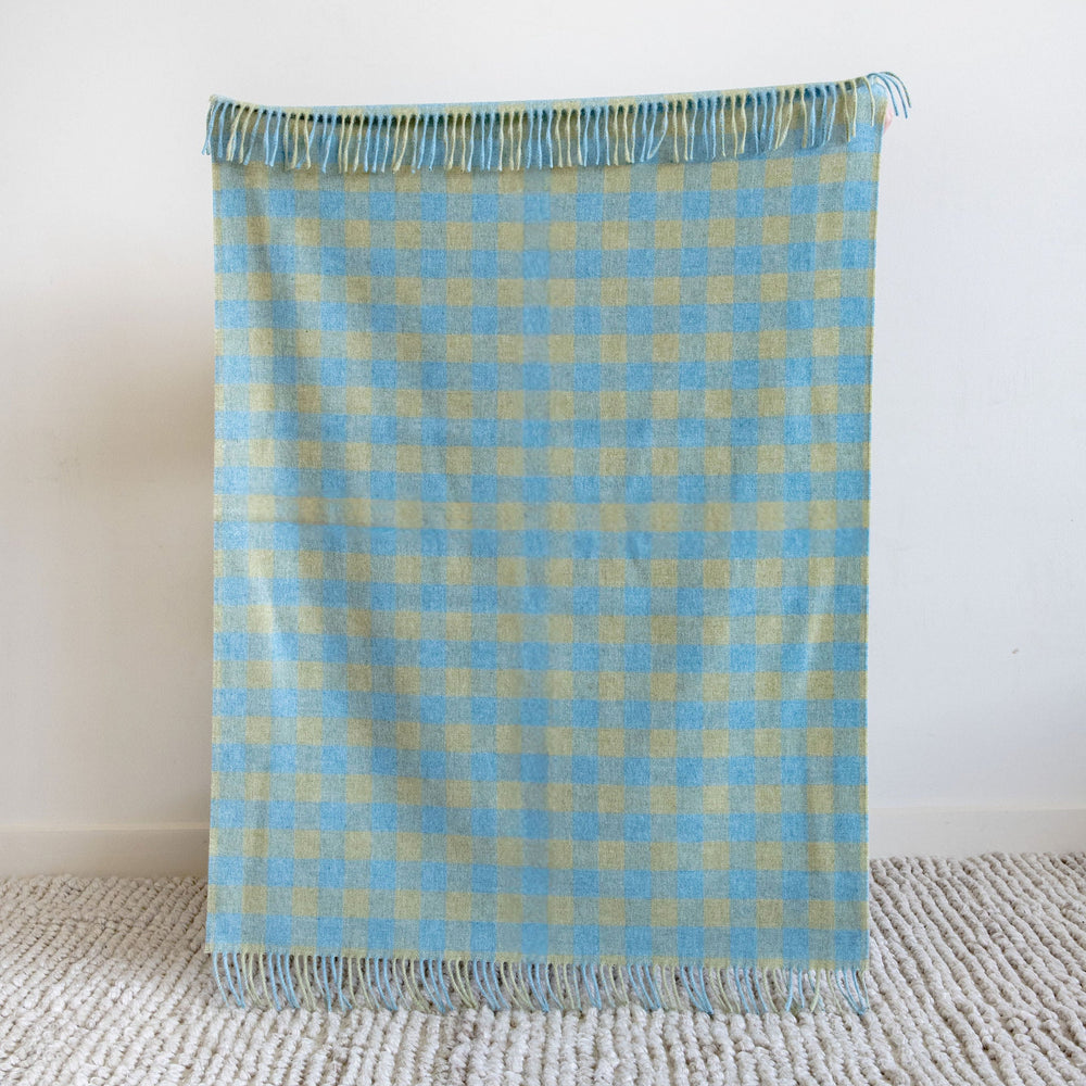 Blue and green checkered blanket on a textured surface with a white background