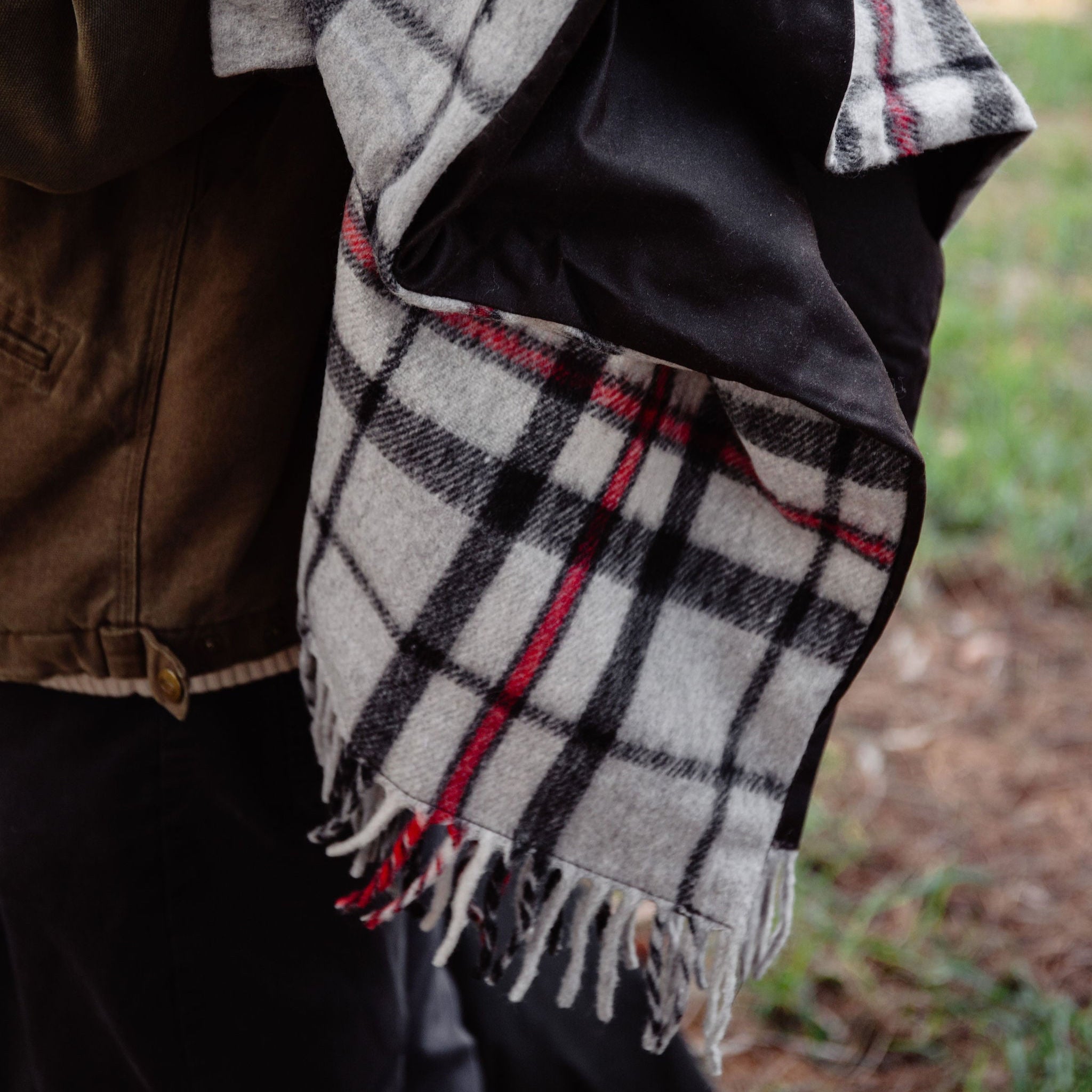 Plaid scarf draped over a person with a blurred outdoor background