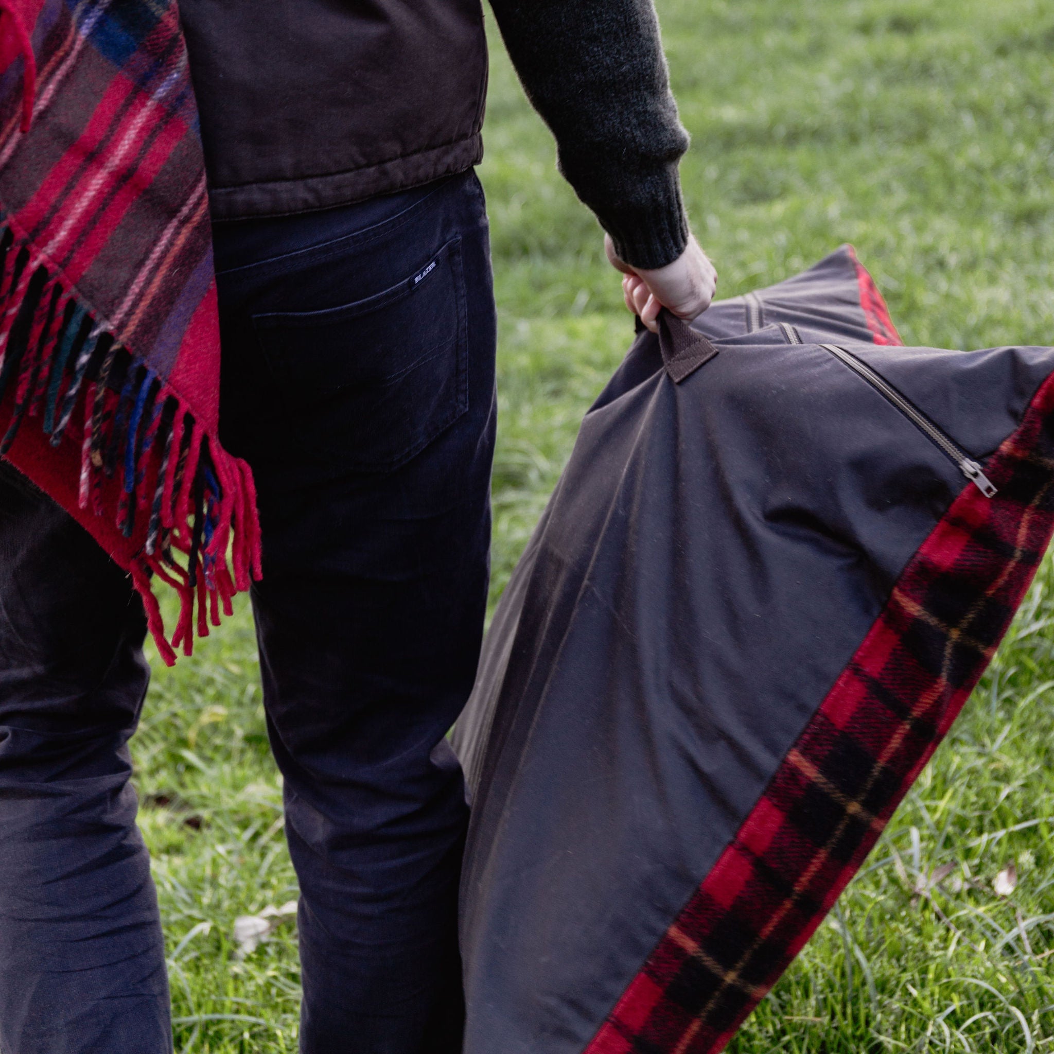 Person holding a plaid blanket and plaid outdoor cushion