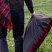 Person holding a plaid blanket and plaid outdoor cushion