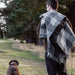 Man walking a dog in a field with a checkered blanket draped over his shoulders