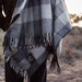 Person wearing a plaid poncho with a logo in an outdoor setting