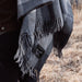 Person wearing a gray plaid blanket over their shoulders with a visible brand logo in a natural setting.