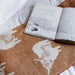 Open book on a world map with a teddy bear on a white surface