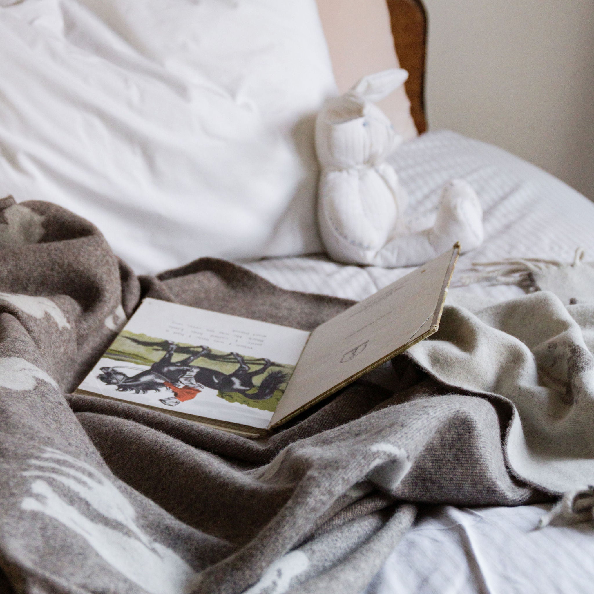 Book and plush toy on a bed with white bedding and brown headboard