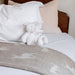 Bed with white bedding, brown headboard, and knitted white bear toy.