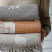 Stack of patterned blankets held by a person wearing a Fair Isle sweater.