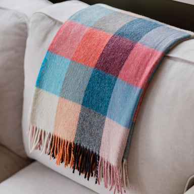 Colorful checkered blanket draped over a beige sofa