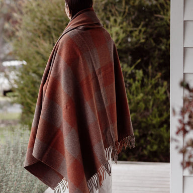 Person wearing a brown blanket over their shoulders on a porch