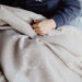 Child wearing a navy blue sweatshirt, sitting on a beige blanket.