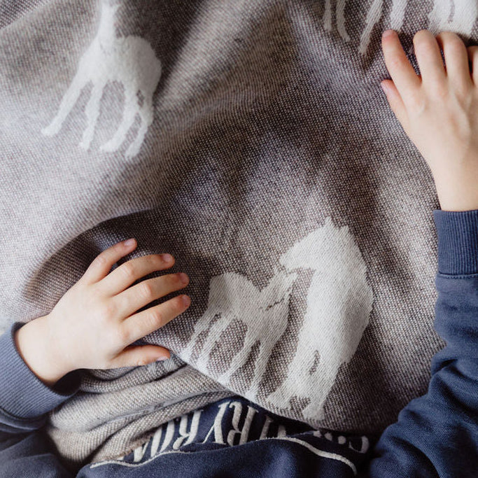 Person wrapped in a patterned blanket with visible hands