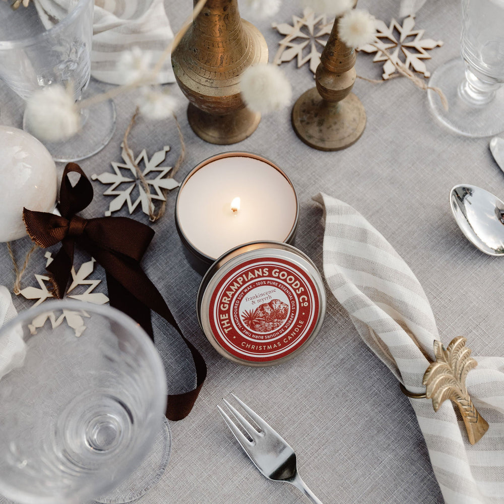 Table setting with candles, glasses, and decorative elements on a gray tablecloth.