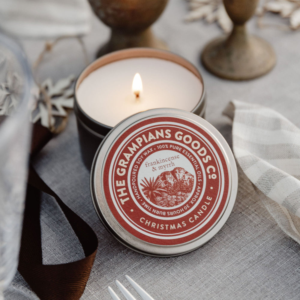 Candle with 'The Grandians Goods' label on a table with decorative elements