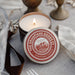 Candle with 'The Grandians Goods' label on a table with decorative elements