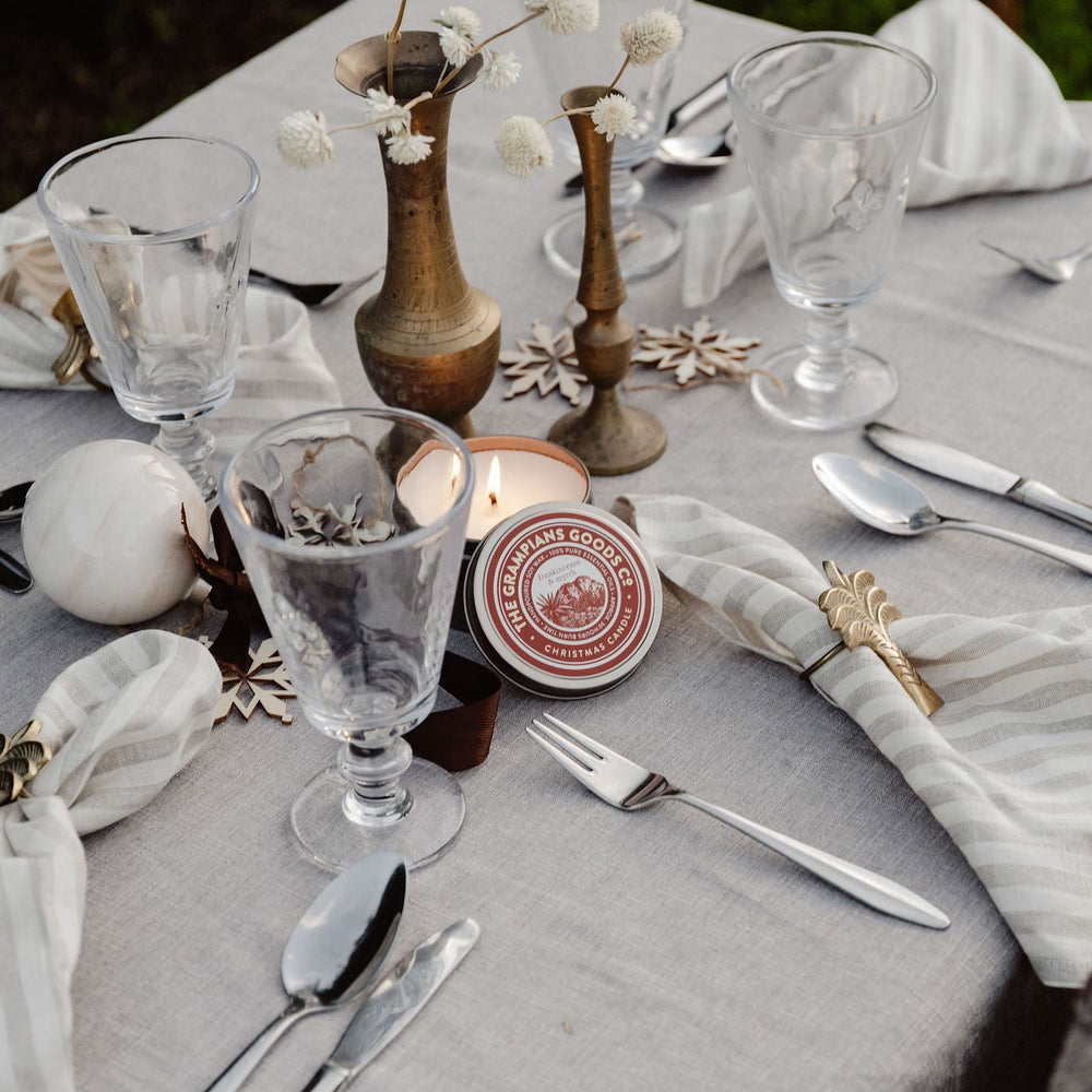 Elegant table setting with gray tablecloth, glassware, cutlery, and decorative items.