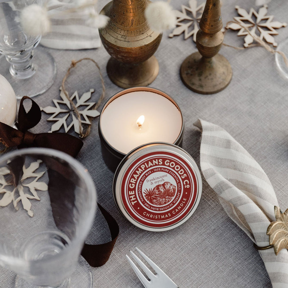 Table setting with candles, glasses, and decorative items on a gray tablecloth.