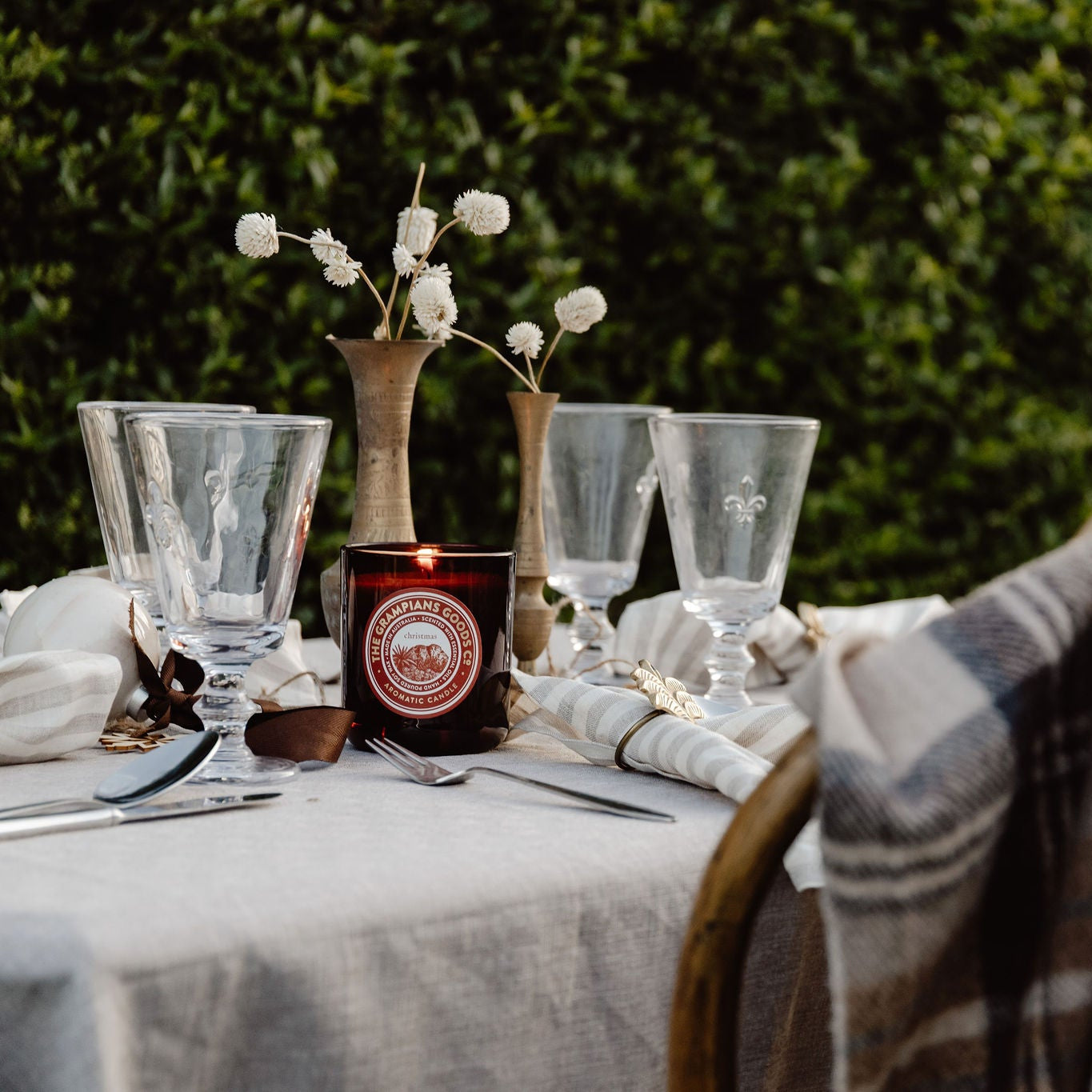 Set table with glasses, candle, and plaid blanket outdoors