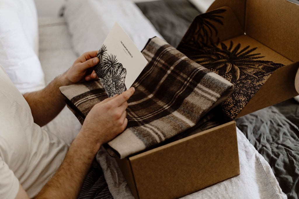 Father's Day 2026 - hands folding tartan blanket beside box